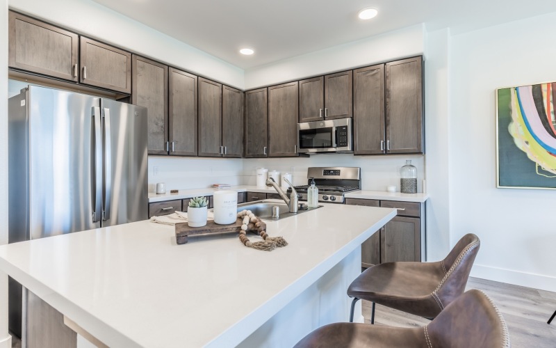 Spacious and well lit kitchen  with wood floors and access to the living room