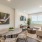 Spacious and well lit living room with wood flooring, large windows and open access to the kitchen